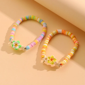 Detalle de pulseras bohemias de cuentas heishi con dijes de estrella de mar y plumeria