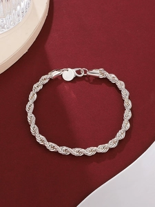 Close-up of silver rope chain bracelet with lobster clasp on a burgundy textured background
