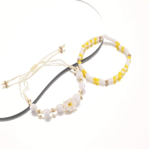 Detalle de set de pulseras bohemias de verano con flor de plumeria y cuentas amarillas