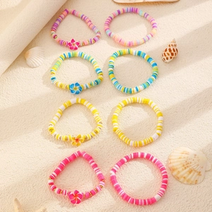 Detalle de 8 pulseras Heishi bohemias con flores de plumeria y cuentas de arcilla de colores