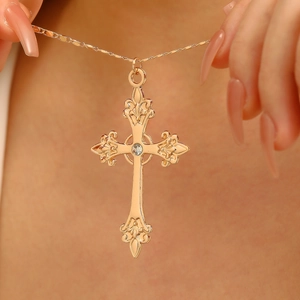 Detail of gold-plated cross pendant with sparkling crystal inlay on a delicate chain