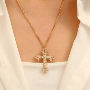 Close-up of golden vintage cross necklace with detailed embossing and rhinestones