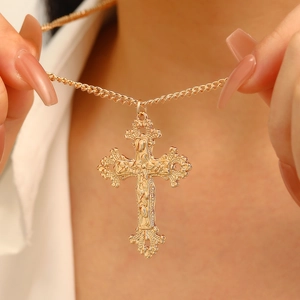 Detailed close-up of a vintage baroque gold cross necklace with intricate carvings