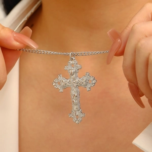 Macro detail of large vintage silver cross necklace with ornate baroque floral carvings