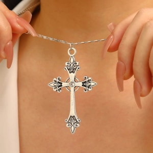 Detail of silver gothic cross necklace featuring baroque floral carving and center zircon