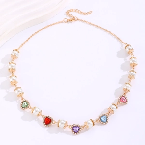 Detail of colorful heart gemstone necklace with pearls and gold settings on white base
