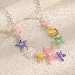 Dettaglio dei ciondoli a forma di stella marina e conchiglia con perle sulla collana