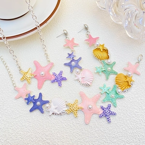 Set di gioielli con stelle marine colorate e conchiglie con perle su sfondo chiaro