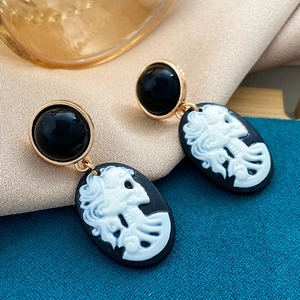 Makro-Detail der Vintage-Ohrringe mit weißem Totenkopf-Kamee auf schwarzem Hintergrund