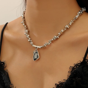 Vue macro de la chaîne de perles géométriques argentées avec pendentif cœur en pierre