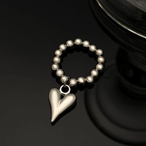 Vue détaillée du bracelet en perles argentées avec un pendentif en forme de cœur allongé