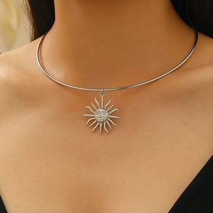 Macro shot of silver sun face pendant with irregular rays on polished metal choker