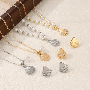 Macro view of shell-shaped necklaces and earrings with pearls on pleated background