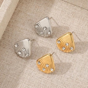 Detailed view of shell-shaped stud earrings in gold and silver plating with clear crystals