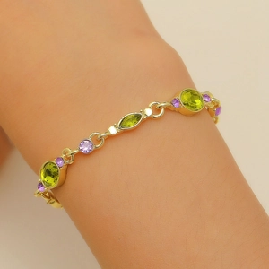 Detail of gold-plated bracelet featuring green oval crystals and purple round zircons