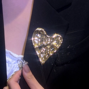 Broche cœur dorée irrégulière texture métal liquide sur revers de costume noir