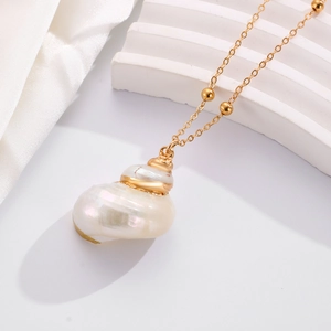 Macro shot of seashell pendant necklace with gold plated edges and elegant gold beads