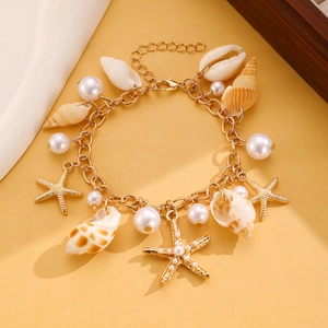 Detail of bohemian gold bracelet with natural shells, starfish charms and faux pearls