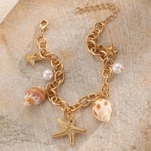 Detail of beach style gold chain bracelet with starfish charms, shells and white pearls