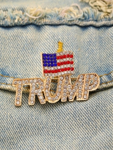 Λεπτομερής προβολή καρφίτσας Trump με αμερικανική σημαία και στρας σε φόντο τζιν υφάσματος