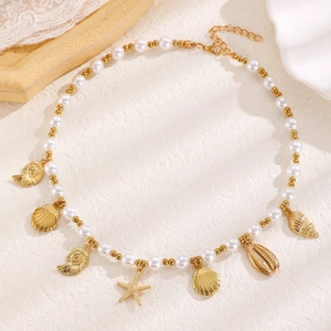 Detail of bohemian necklace with golden seashell, starfish charms and faux pearls