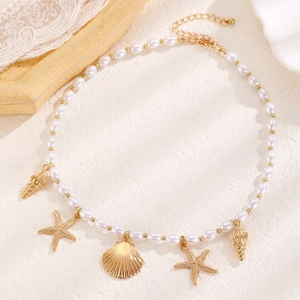Bohemian pearl necklace with starfish and seashell charms on a sandy beige background