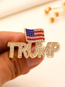 Κοντινή λήψη χρυσής καρφίτσας Trump με αμερικανική σημαία και λαμπερά στρας