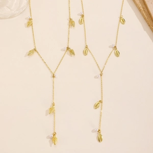 Close-up of golden sea shell, conch pendants and small white pearls on thin Y-shaped necklace