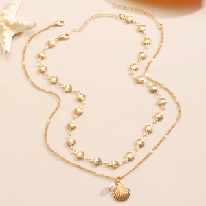 Detailed close-up of double-layer gold shell necklace with pearl and starfish decor