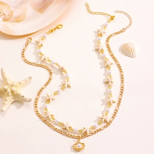 Detail of layered beach necklace with starfish beads, pearls and golden shell pendant