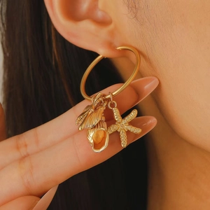 Détail de créoles dorées vintage avec breloques étoile de mer, coquillage et insecte