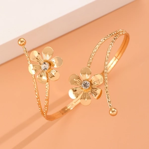 Gros plan du bracelet spirale doré avec texture tressée et deux fleurs en strass