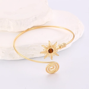 Détail d'un bracelet de bras soleil doré avec pierre œil de tigre sur pierre blanche