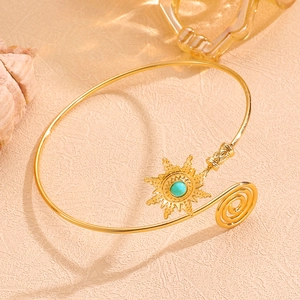 Gros plan détaillé du bracelet soleil doré orné d'une perle turquoise sur sable chaud