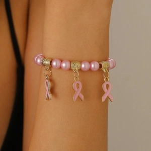 Gros plan du bracelet en perles roses avec séparateurs dorés et breloques ruban rose