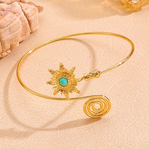 Détail d'un bracelet de bras bohème doré avec pierre turquoise et motif soleil