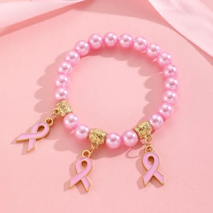 Détail d'un bracelet de perles roses avec des breloques ruban dorées sur soie
