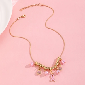 Détail du collier chaîne serpent dorée avec pendentif ruban rose et breloques