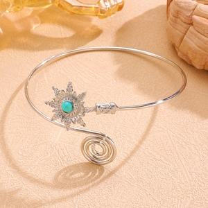 Gros plan détaillé d'un bracelet de bras boho argenté avec fleur et pierre turquoise