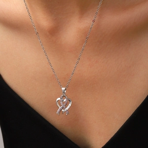 Détail du collier pendentif ruban cœur argenté avec pierres roses et gravure Love life