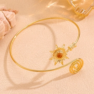 Détail d'un bracelet de bras spirale doré avec totem solaire et pierre ambrée