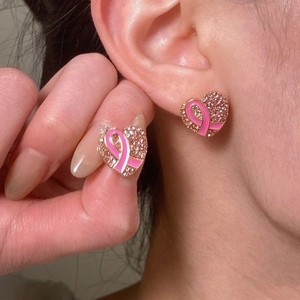 Gros plan de boucles d'oreilles cœur ruban rose avec cristaux étincelants sur l'oreille
