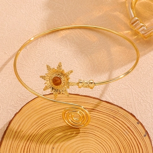 Détail d'un bracelet doré bohème avec motif soleil et pierre brune sur du bois