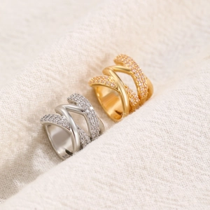 Detail of interlocking gold and silver rings with cubic zirconia on textured fabric
