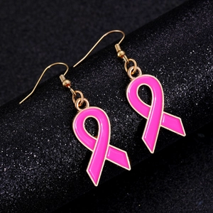 Détail de boucles d'oreilles ruban rose avec bords dorés sur un support brillant