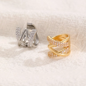 Crossed layered gold and silver ear cuffs with sparkling cubic zirconia on fabric background
