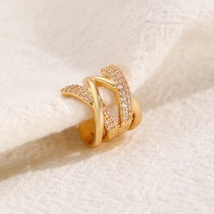 Macro shot of gold-plated triple-layer cross ear cuff featuring sparkling cubic zirconia