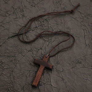 Detail of wooden cross pendant with brown cord on a vintage black textured backdrop