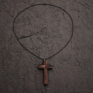 Detailed macro view of vintage wooden cross pendant with black metal beaded chain