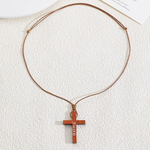 Detail eines Holzkreuz-Anhängers mit weißer Faith-Gravur an verstellbarer brauner Kordel